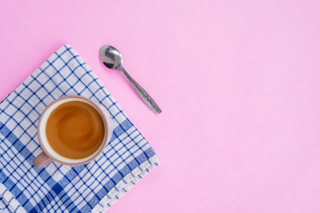 ピンクの背景に分離されたミルクコーヒー、スプーン、青い布、最小限のコンセプトのアイデア。