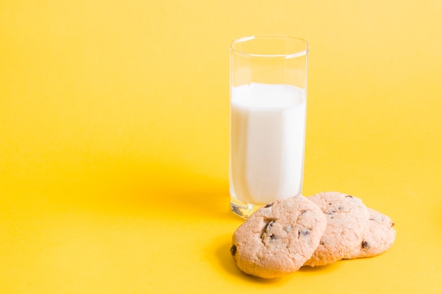 黄色の背景のコピースペースに牛乳とクッキー