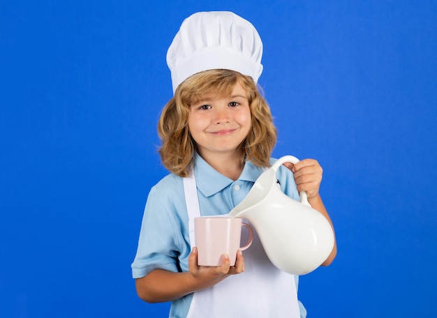 キッチンスタジオpで野菜を準備する調理器具の制服とシェフの帽子を身に着けている子供のためのミルク