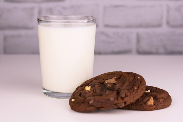 Milk in a glass and chocolate homemade cookies on a white background