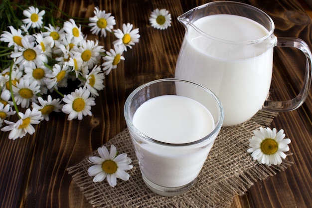 Milk in the glass and jug on the rustic wooden background