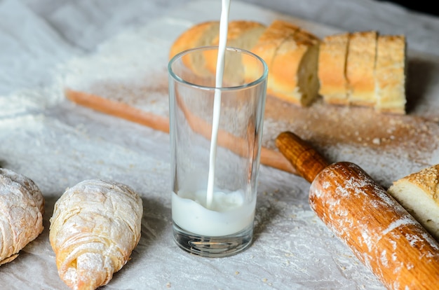Milk is poured into a glass, bread, croissants