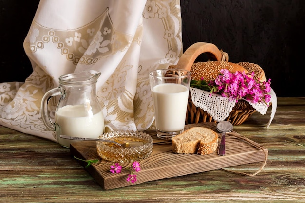 Milk in a jar and a glass bread in a wicker basket and honey on a wooden table closeup