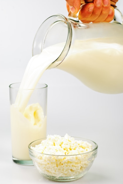 Milk in jug and glass and curds on white