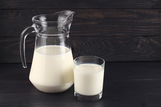 Milk in a jug and a glass on dark boards 