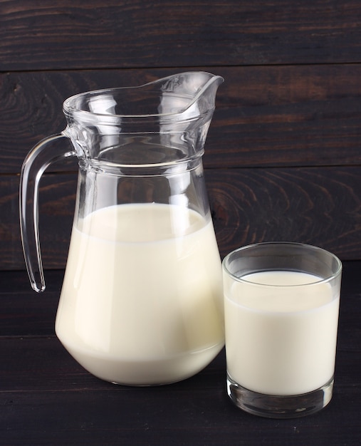 Milk in a jug and a glass on dark boards