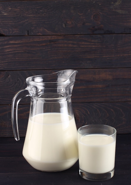 Milk in a jug and a glass on dark boards