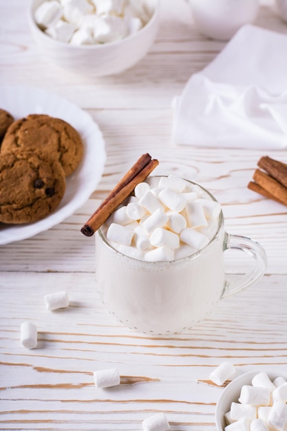 Milk latte with marshmallows in a cup and a plate with homemade cookies Comfort food Vertical view