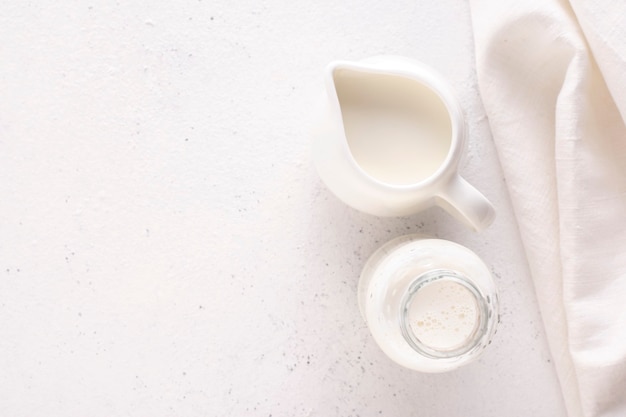 Milk in a milk jug and bottle on a white background with copy space, top view.