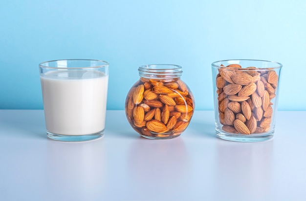 Milk and nuts on and a glass and a jar on blue background