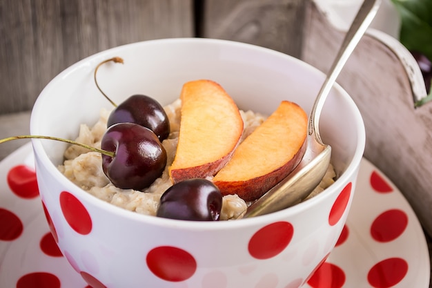 Milk oatmeal porridge with fruits: peaches and cherries. Healthy breakfast