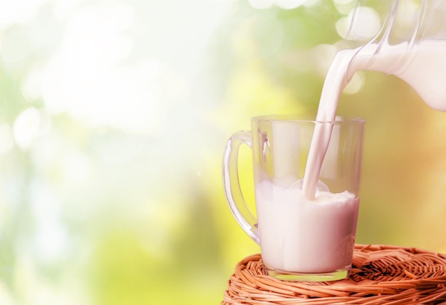 Milk pouring in glass on blurred background