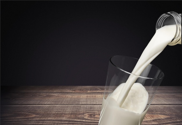 Milk pouring in glass on grass background