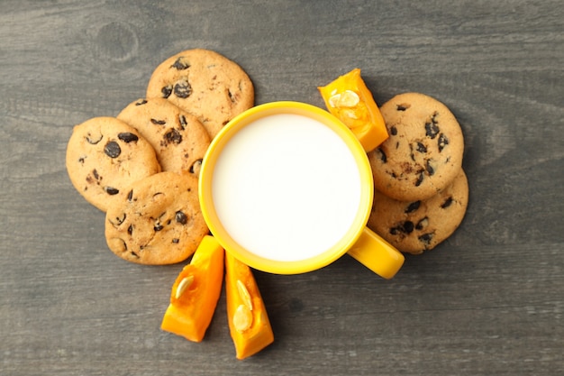 Milk and pumpkin cookies on gray wooden table.