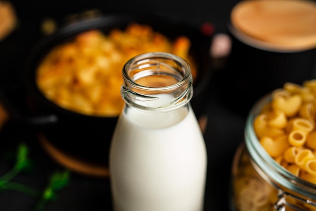 マカロニとチーズのソース用ミルク、暗い背景に安っぽいソースのアメリカンスタイルのマカロニパスタ。高品質の写真