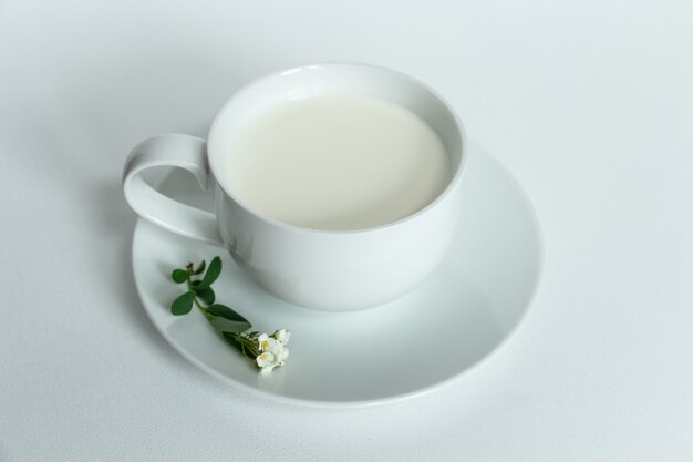 milk in a white cup on a white background