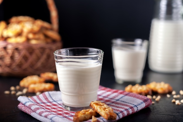 Milk with freshly baked homemade peanut cookies on dark surface