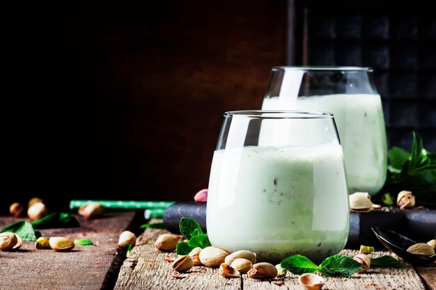 Milkshake smoothies with pistachio ice cream and mint vintage wood background selective focus