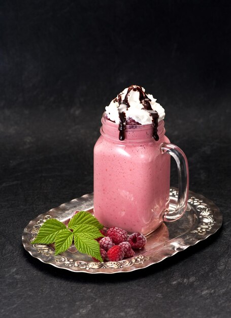 Milkshake with raspberries cream and chocolate syrup in a glass jar