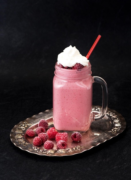 Milkshake with raspberries and cream in a glass jar