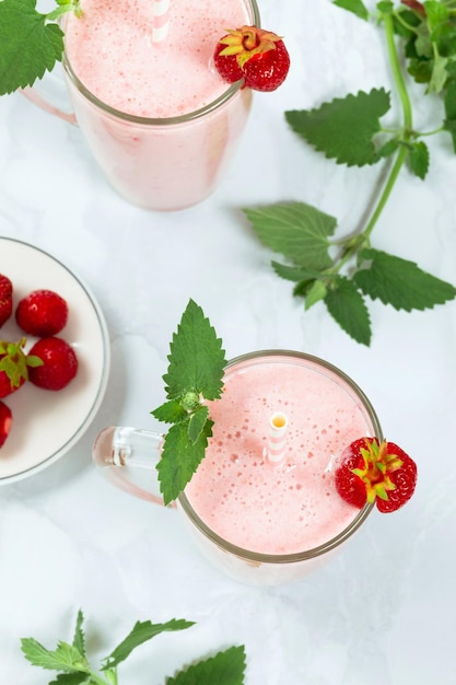 Milkshake with strawberries in a glass glass with melissa leaves in the design top view