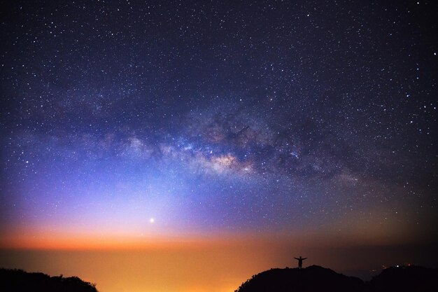 Milky way galaxy and silhouette of a standing happy man on Doi Luang Chiang Dao