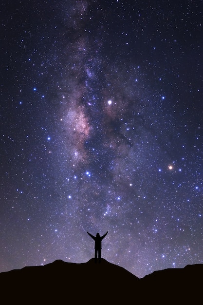 Milky way galaxy and silhouette of a standing happy man