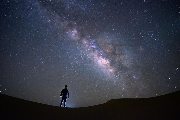 写真 タール砂漠で立って眺めている男のミルクウェイ銀河 ジャイサルメール インド 宇宙写真