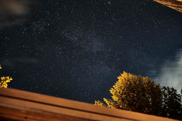 Milky way in the night sky over a cabin in the woods with clouds