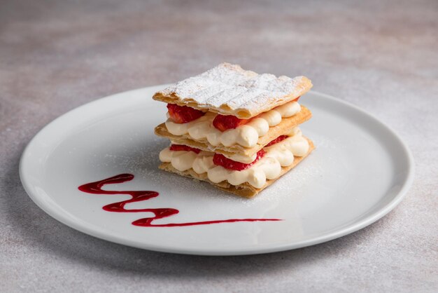 Millefeuille food on a white plate wiht millefeuille isolated
on white and grey background