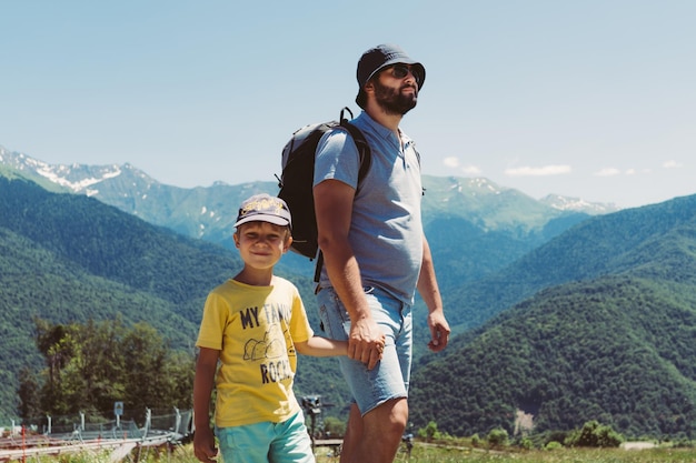 millenial bearded tourist man hiking in mountains with child. Father and son spend time together