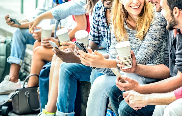 Foto gruppo di amici millenari che usano lo smartphone con il caffè all'università