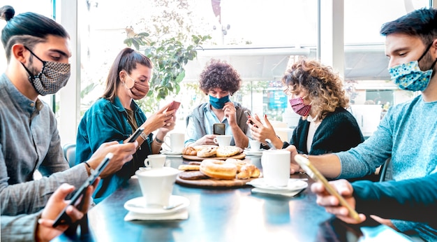 Millenial people using mobile smart phones at coffee bar - Focus on central frame guy