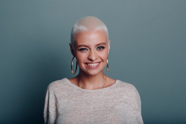 Millenial young woman with short blonde hair winks smiling portrait