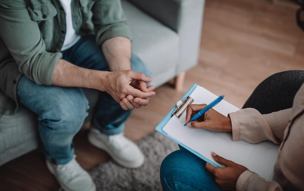 Millennial african american woman psychologist listens to european patient takes notes in clinic