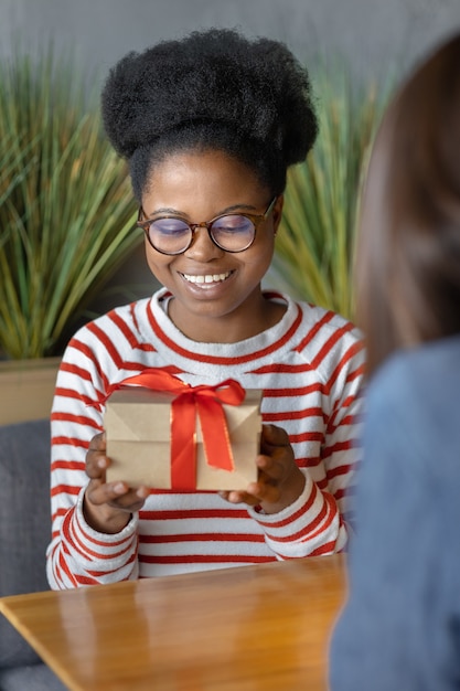 ミレニアル世代のアフリカ系アメリカ人女性がガールフレンドから贈り物を受け取る