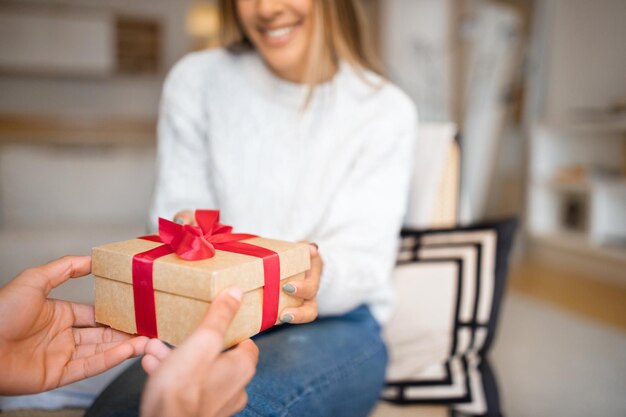 Millennial arab guy gives box with present to european woman congratulates with Valentine day