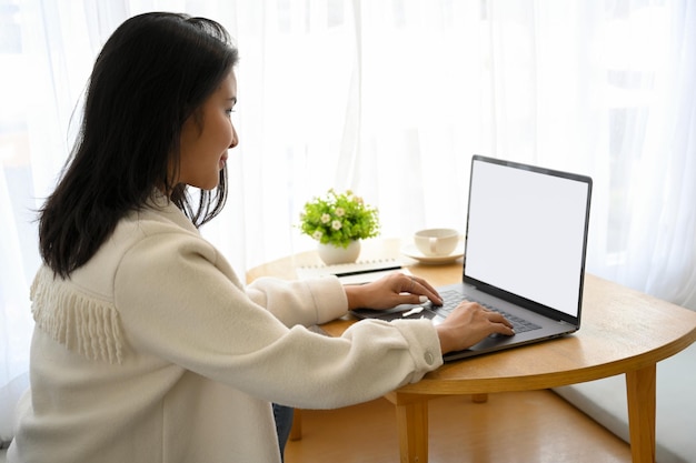 Millennial asian freelance femminile che lavora a distanza presso il bellissimo caffè che lavora su un computer portatile