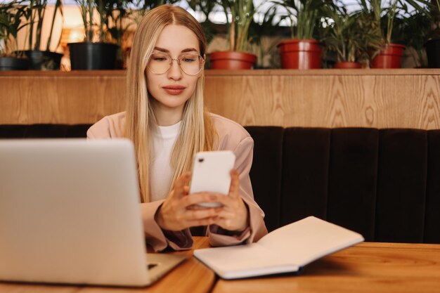 Photo a millennial business woman with glasses works using a mobile phone and technology in a cafe