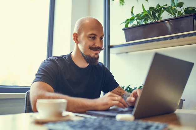 Millennial caucasian man works on computer at home office\
distance job