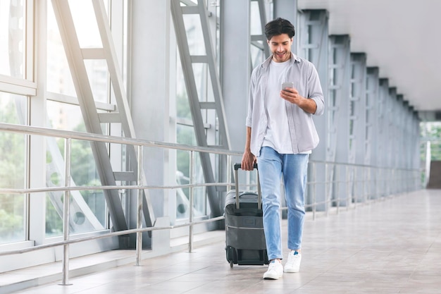 Ragazzo millenario che controlla i messaggi in arrivo dopo l'arrivo in aeroporto