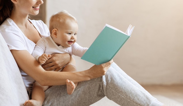 Millennial mom reading book to her baby boy at home