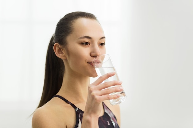 Millennial woman drinking clean fresh water after training