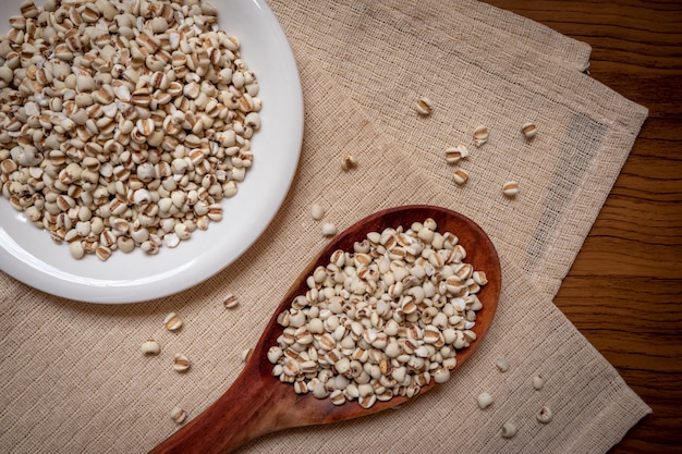 Foto miglio in un cucchiaio di legno che è cereali e cibo su una tovaglia marrone