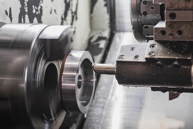 A milling cutter in a CNC machine cuts a metal workpiece that rotates at high speed