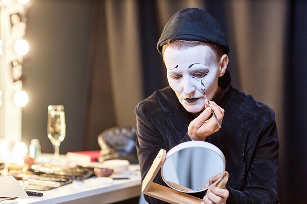 Foto mime che si guarda nello specchio dietro le quinte e si trucca