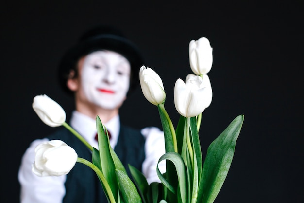 Mime stands behind bouquet of white tulips