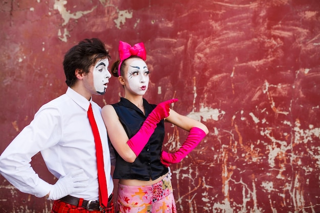 Photo mimes standing on a red wall