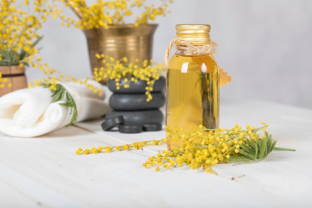 Mimosa flowers massage oil  in glass bottle. Closeup