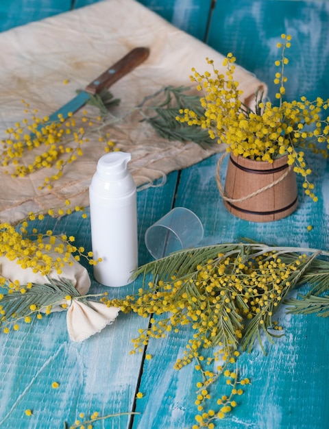 Mimosa gezichtscrèmedispenser op een cyaan houten ondergrond. Detailopname